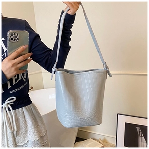 Detail of light blue crocodile embossed bucket bag with fashion leather stamp and strap