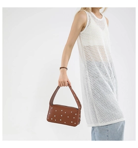 Detail view of brown pebbled leather handbag with silver studs and wide shoulder strap
