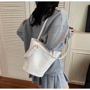 Detail of white crocodile texture bucket bag with silver metal ring and embossed logo