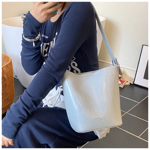 Detail of light blue crocodile pattern bucket bag with adjustable shoulder strap