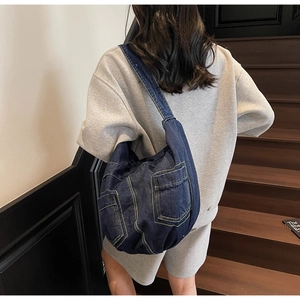 Detailed view of dark blue denim crossbody bag featuring contrast yellow stitching and pockets