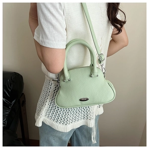 Side view of a mint green pebbled leather crossbody bag worn with a white textured top