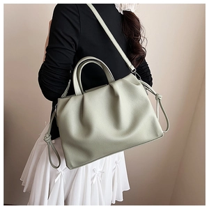 Detail view of light green pleated shoulder bag with soft cloud texture and knot details