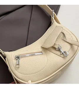 Detail of light beige litchi grain faux leather bag with stylish silver metal hardware