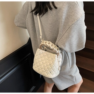 Quilted off-white bucket bag with rhinestones shown on model in outdoor staircase setting