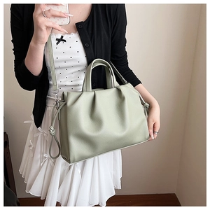 Detail view of the soft light green pleated bucket bag texture and top handles
