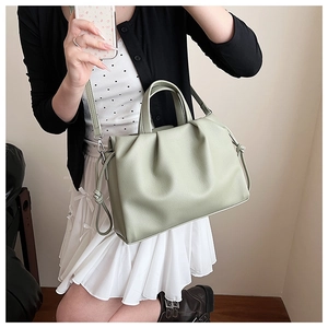Details der hellgrünen Schultertasche mit Plissee, Doppelgriffen und abnehmbarem Gurt