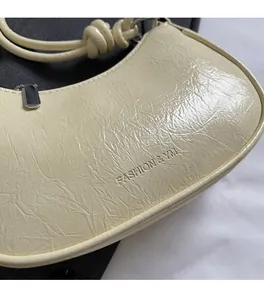 Close-up of semi-circle crossbody bag with glossy pleated texture and silver zipper detail