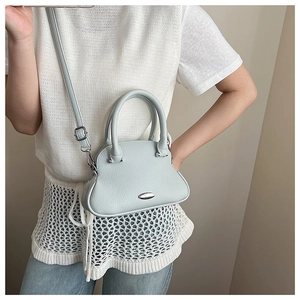 Detail of light blue crossbody bag with lychee grain texture and silver metal accent