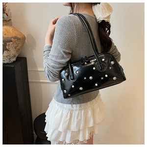 Detail of black patent leather shoulder bag with white pearls and silver star studs