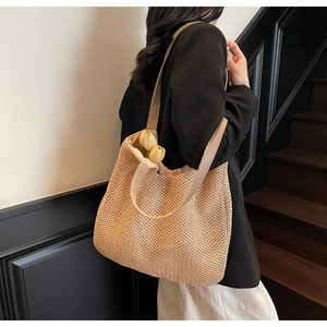 Detail of hand-woven straw shoulder bag with reinforced straps and natural khaki texture