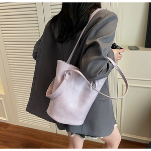 Detail of lavender stone-textured bucket bag with embossed logo on a grey blazer