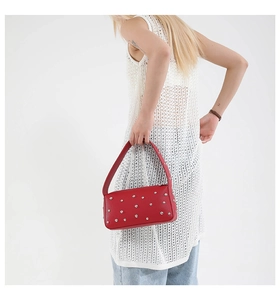 Dettaglio della borsa a spalla in pelle rossa con borchie metalliche argentate lucide