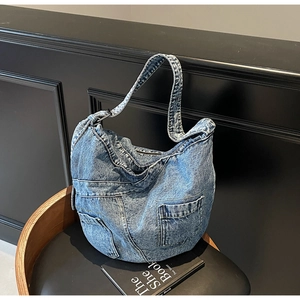 Detail of vintage washed blue denim hobo bag featuring functional pocket and soft texture