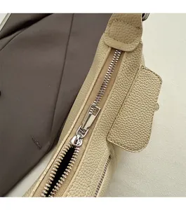 Close-up of smooth silver zipper and litchi texture on beige shoulder bag detail