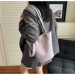 Detail of light purple crocodile embossed leather bucket bag with brand logo and strap