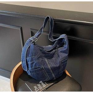 Detail of deep blue denim crossbody bag featuring contrast yellow stitching and utility pockets