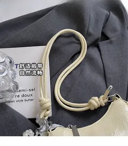 Close-up of off-white leather shoulder bag with knotted strap and pearl charm detail