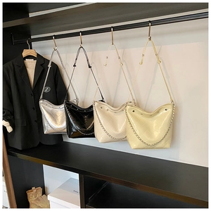 Detail of quilted bucket bags in silver, black, white and yellow with metal chain straps