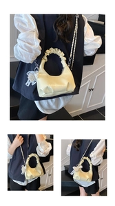 Détail d'un sac coquille blanc cassé plissé avec breloque perle et bandoulière
