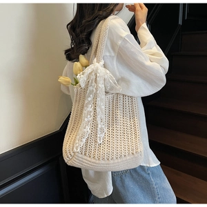 Detail of woven beige tote bag featuring intricate crochet patterns and lace bow accent