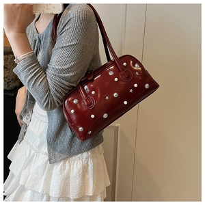 Close-up of deep red glossy shoulder bag with pearls and silver star studs detail