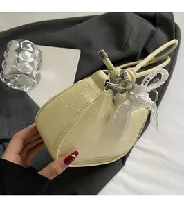 Detail of light yellow heart-shaped handbag featuring pleated texture and lace bow charm