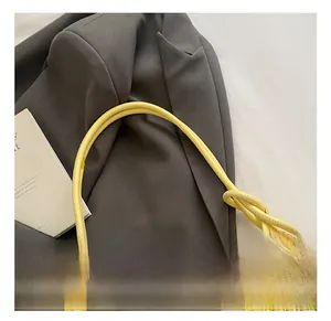 Détail de la texture tissée d'un sac à main jaune et blanc avec poignées arrondies