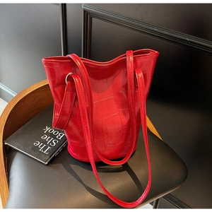 Detailed close-up of red crocodile texture on minimalist faux leather bucket bag