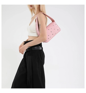 Detailed close-up of pink pebbled leather shoulder bag featuring silver metal studs
