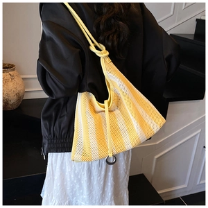 Detail of yellow striped mesh tote bag with knot strap and metallic ring accessory