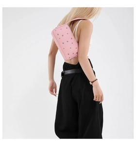 Detailed close-up of pink leather underarm bag featuring silver rivet metal studs decoration