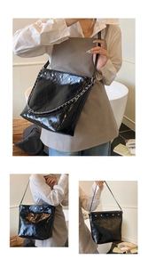 Detail of black quilted leather bucket bag with silver studs and chain strap