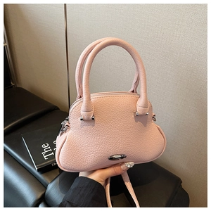 Detail of pink lychee leather shell bag featuring silver metal buckle and zip closure