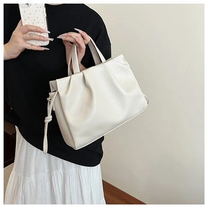 Close-up of a creamy white pleated crossbody bag with knot drawstring detail and soft PU texture