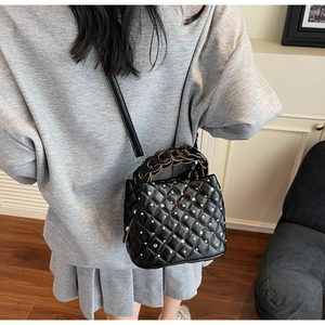 Detail of black quilted crossbody bag with sparkling rhinestones and woven handle