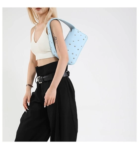 Detail of light blue leather underarm bag with silver studs and millennium retro style
