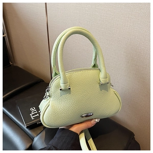 Detail of mint green lychee grain leather handbag with curved handle and silver buckle