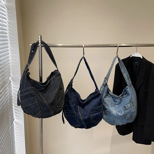 Three denim crossbody bags in grey and blue washes hanging in a minimalist studio setting