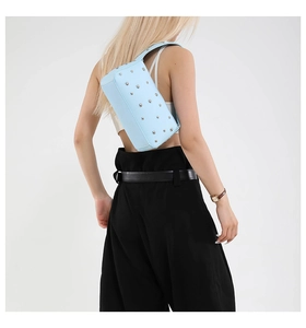 Detail of light blue grain leather underarm bag with silver stud accents on model