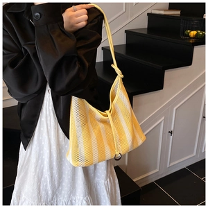 Detail of yellow and white striped mesh tote bag with metal ring and knotted strap