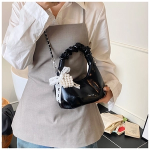 Détail du sac à main verni avec nœud en dentelle et breloque cœur en perle fine