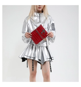 Detail of red crocodile texture bag with silver cross and metal chain decoration