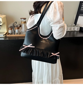 Detail view of black tote bag with pink wave trim and chiffon lace bow on a model