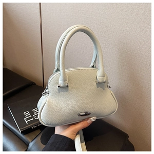 Detail view of mint green lychee grain leather shell bag with circular handles