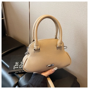 Macro detail of beige pebble grain leather texture on a stylish shell shaped handbag