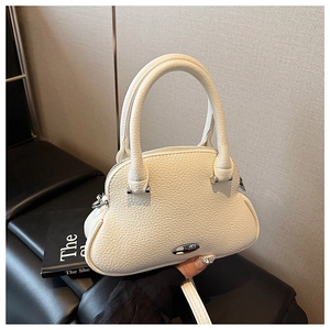 Detail view of white lychee textured crossbody shell bag with silver metal handle and clasp