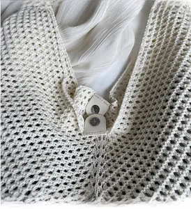 Detailed close-up of woven cream tote bag showing the magnetic snap closure and texture
