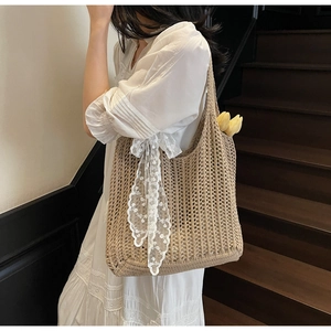Detail of beige woven tote bag featuring white lace ribbon bow and a floral accent