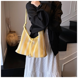 Detail of yellow hollow mesh tote bag with leather knotted handle and metal ring